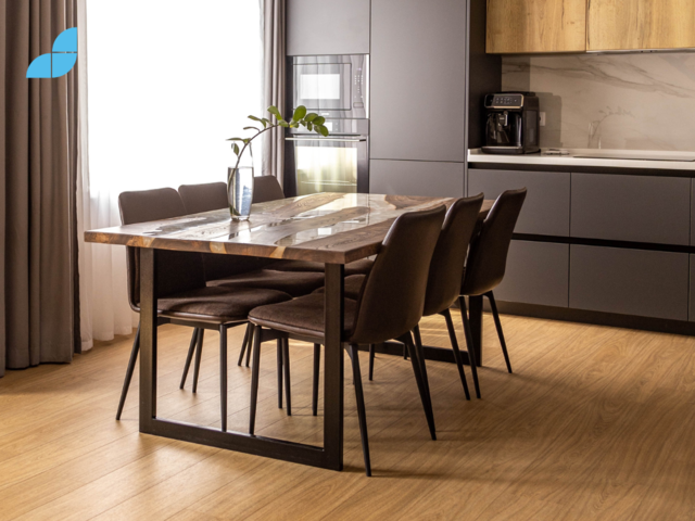 A dining table in front of the kitchen furniture. 